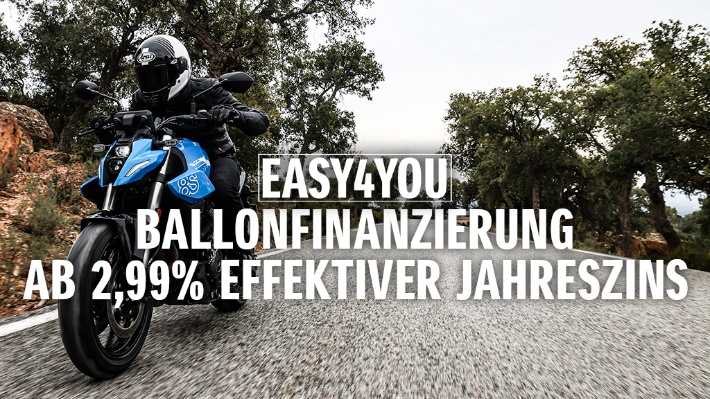 Ein Motorradfahrer auf einer blauen Suzuki GSX-8S fährt dynamisch über eine Landstraße durch bewaldetes Gelände. Im Vordergrund steht der Hinweis auf die „EASY4YOU Ballonfinanzierung ab 2,99 % effektiver Jahreszins“.