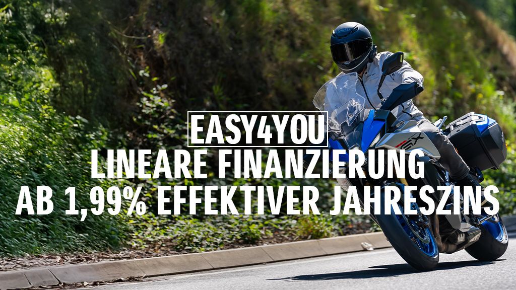 Ein Motorradfahrer auf einer Suzuki GSX-S1000GX fährt eine sonnige Landstraße entlang. Im Vordergrund wird die EASY4YOU lineare Finanzierung mit 1,99 % effektivem Jahreszins beworben.