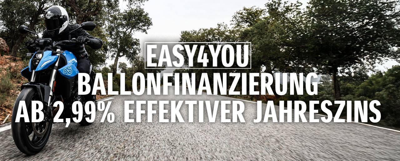 Ein Motorradfahrer auf einer blauen Suzuki GSX-8S fährt dynamisch über eine Landstraße durch bewaldetes Gelände. Im Vordergrund steht der Hinweis auf die „EASY4YOU Ballonfinanzierung ab 2,99 % effektiver Jahreszins“.