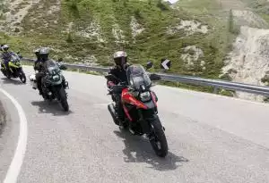 Rote Suzuki V-Strom führt eine Gruppe Motorräder auf einer malerischen Gebirgsstraße an.