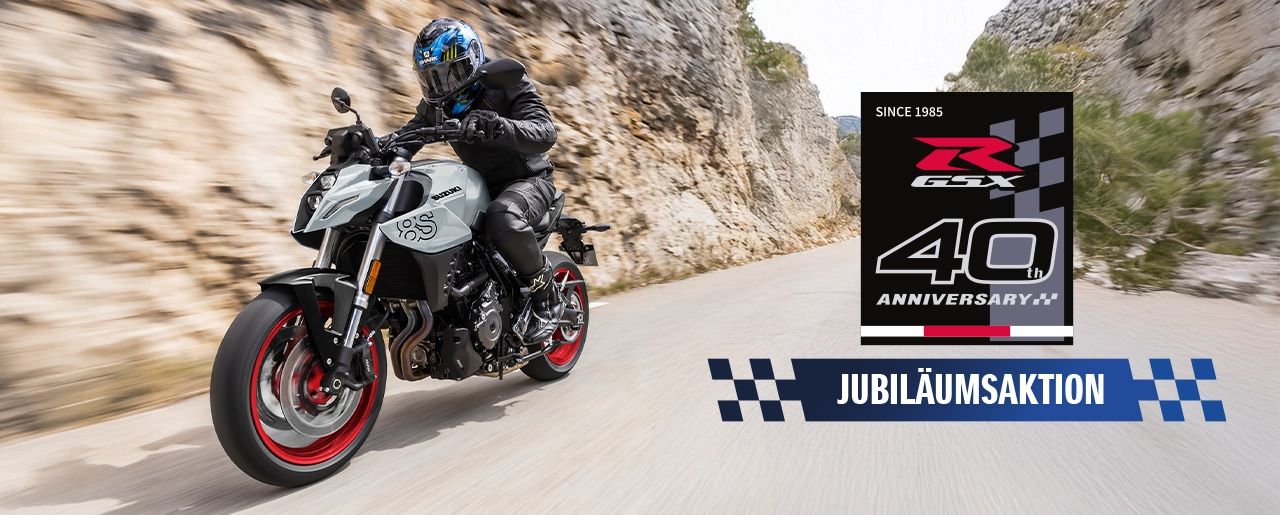 Graue GSX-8S auf Bergstraße, rechts unten Jubiläumsaktions-Logo