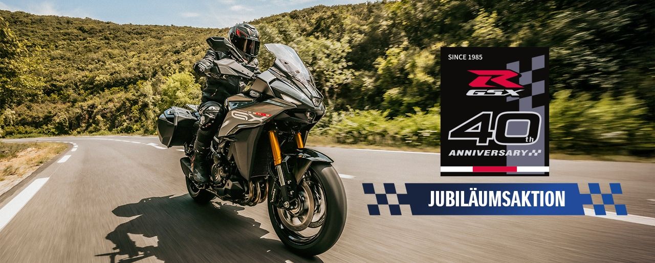 Eine graue GSX-S1000GX auf einer Landstraße, rechts unten mit Jubiläumsaktions-Logo