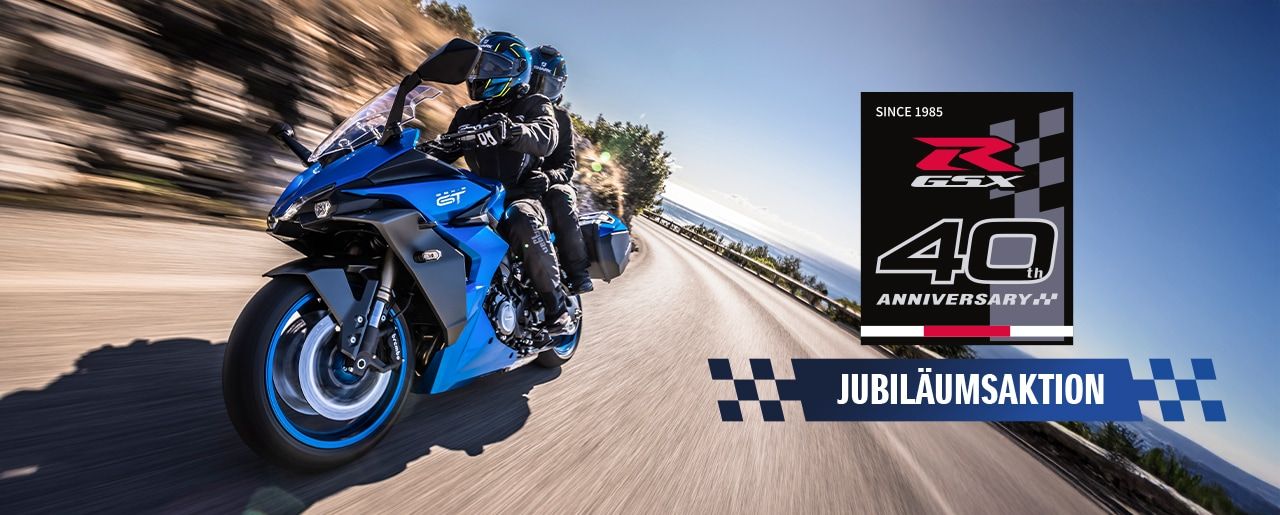 Eine blaue GSX-S1000GT mit zwei Personen auf einer kurvigen Landstraße, rechts unten mit Jubiläumsaktions-Logo