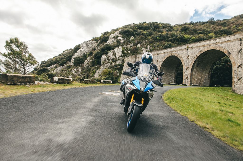 Ein Suzuki Motorrad vor einer Brücke, die von einer kurvigen Landstraße gekreuzt wird