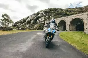 Ein Suzuki Motorrad vor einer Brücke, die von einer kurvigen Landstraße gekreuzt wird
