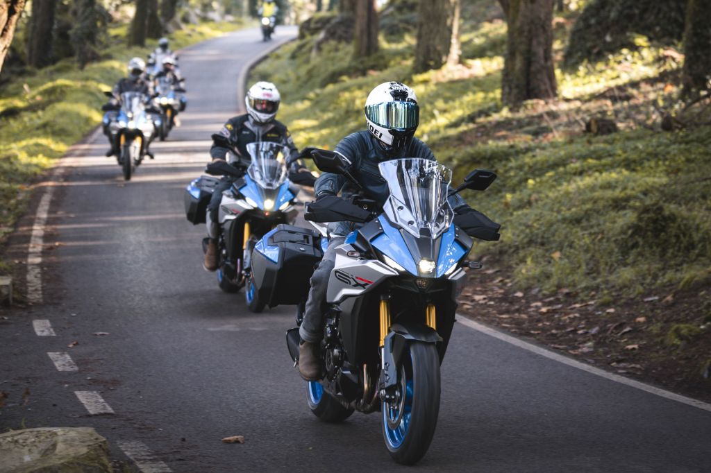 Motorradgruppe fährt durch eine kurvige Waldstraße.