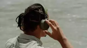 Bild des Kopfs einer Person von hinten aufgenommen, die sich Kopfhörer aufsetzt.