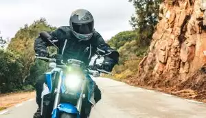 Motorradfahrer auf kurviger Straße in landschaftlicher Umgebung.