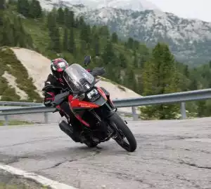 Motorradfahrer auf roter Suzuki V-Strom in kurviger Berglandschaft