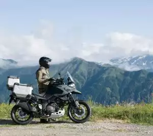 Motorradfahrer auf Suzuki V-Strom vor Berglandschaft.