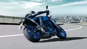 Motorradfahrer auf Suzuki-Motorrad in Kurve mit Stadtpanorama im Hintergrund