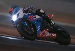 Rennmotorrad von Suzuki in voller Fahrt auf einer Rennstrecke bei Nacht.