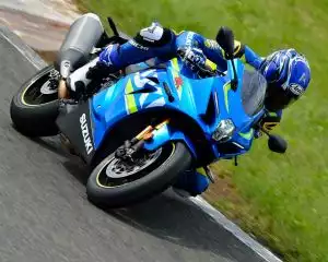 Rennfahrer auf Suzuki-Motorrad in Kurve auf Rennstrecke