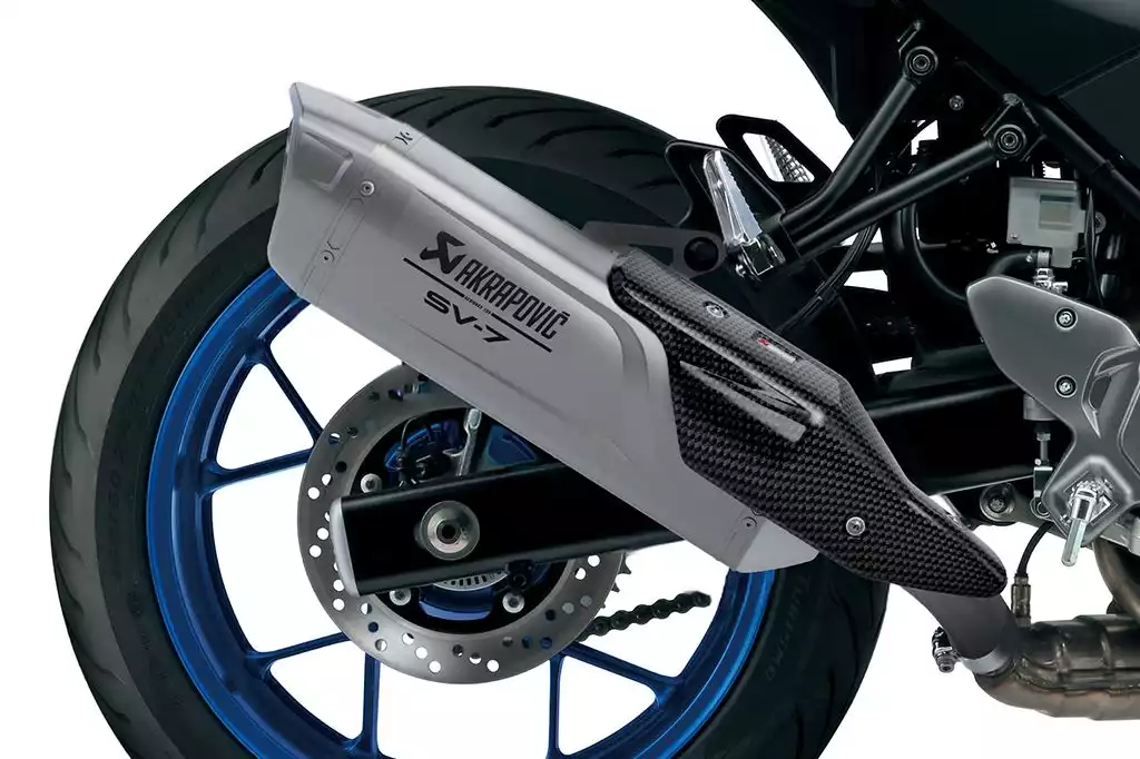 Motorradhinterrad mit blauem Felgenrand und Akrapovič SV-7GX Auspuff mit Carbon-Abdeckung.