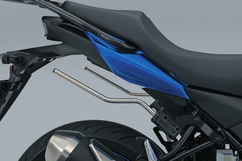 Seitenträger-Halterungen aus Metall, montiert unter der Sitzbank einer Suzuki; zwei stabile, silberne Streben ragen nach hinten für die Befestigung von Seitentaschen.