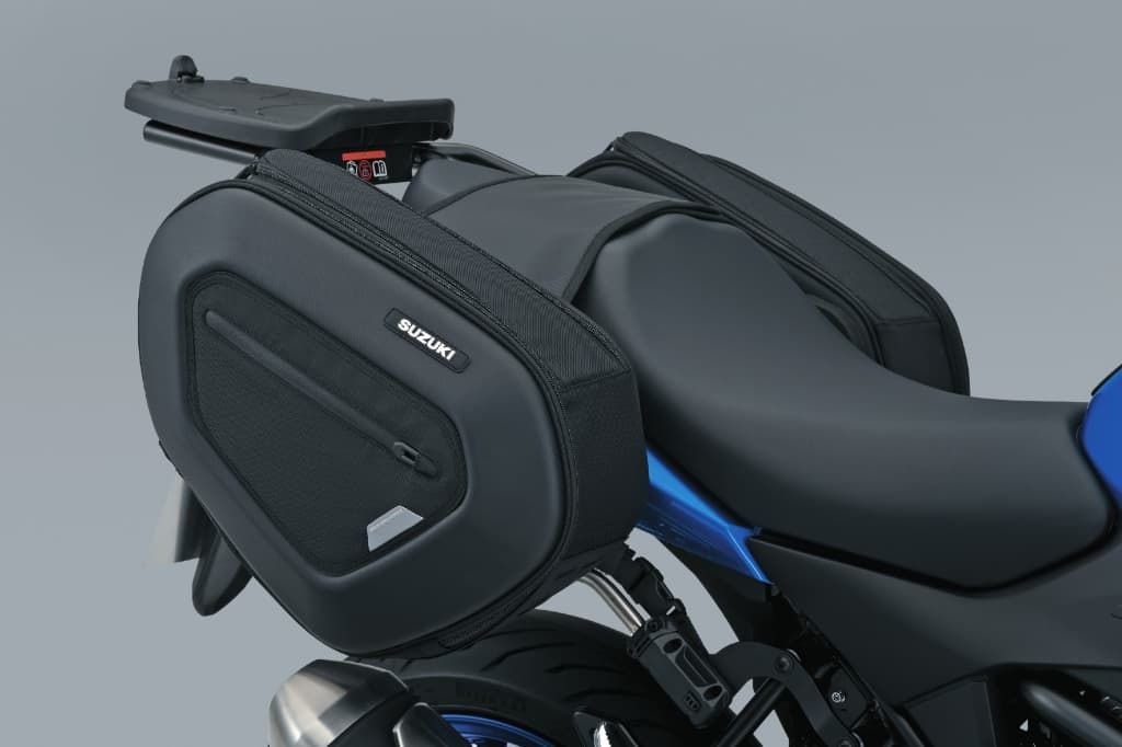 Montierte Seitentaschen an einer Suzuki; zwei schwarze, formstabile Seitentaschen mit Suzuki-Logo sind links und rechts am Trägersystem befestigt.