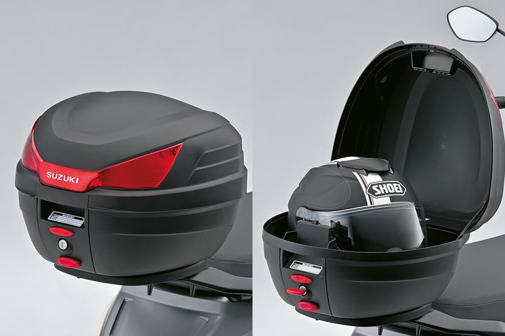 Schwarzes Suzuki-Topcase in geschlossener Ansicht auf einem e-Address Elektroroller; Blick auf Sitzbank, Lenker und Frontpartie.