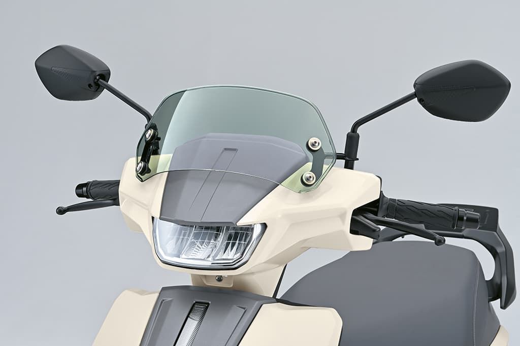 Grün getöntes Windschild (Meter Visor) am Lenkerbereich eines Suzuki e-Address montiert; Fokus auf Frontscheinwerfer und Spiegel.