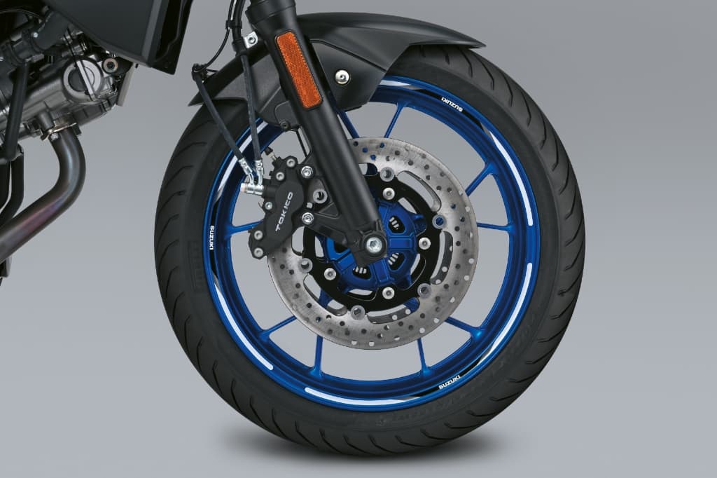 Blauer Vorderrad-Felgenring mit weißen Dekorstreifen an einer Suzuki-Felge; sichtbar sind Bremsscheibe und Bremszange.