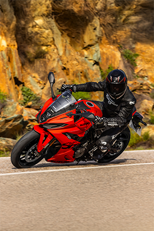 Fahrer auf der GSX-8R DaiDai-Iro Power Edition in sportlicher Schräglage auf kurviger Landstraße