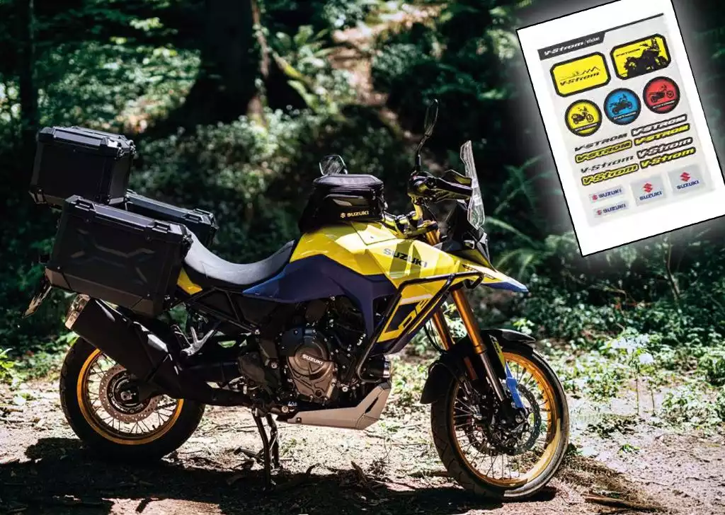 Ein gelbes Suzuki-Motorrad mit robusten schwarzen Seitenkoffern und V-Strom Sticker Set steht auf einem sonnigen Waldweg. Das Motorrad ist umgeben von grüner Vegetation und Sonnenlicht, das durch die Bäume fällt.