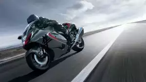 Schwarze Suzuki Hayabusa mit Fahrer in dynamischer Schräglage bei hoher Geschwindigkeit auf offener Straße.