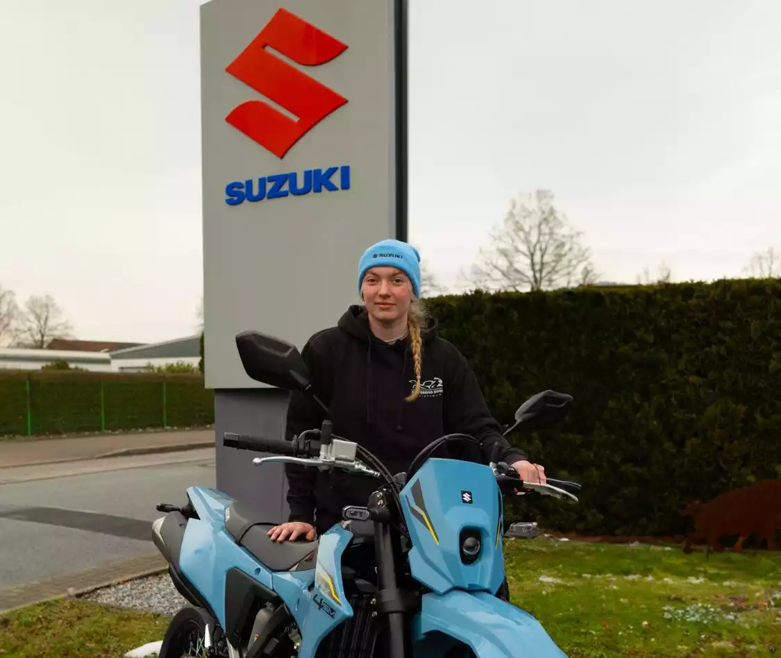 Paula van Zalk steht neben einer blauen Suzuki
