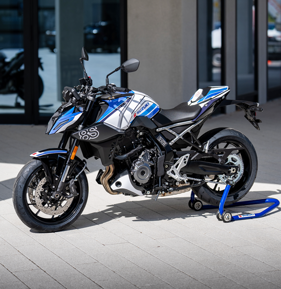 Dreiviertelansicht der weiß-blauen Suzuki GSX-8S Special Edition auf einem blauen Heck-Montageständer im Außenbereich.