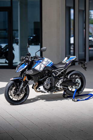 Dreiviertelansicht der weiß-blauen Suzuki GSX-8S Special Edition auf einem blauen Heck-Montageständer im Außenbereich.