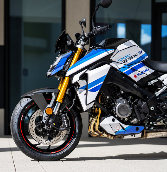 Halbtotale Seitenansicht der Suzuki GSX-S1000 Special Edition mit Fokus auf die goldene Upside-Down-Gabel, den Motor und den Motorspoiler mit der Jubiläumszahl 50.