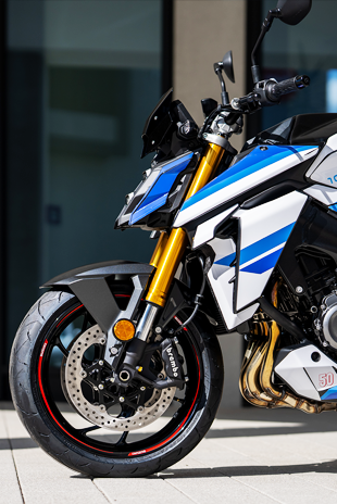 Halbtotale Seitenansicht der Suzuki GSX-S1000 Special Edition mit Fokus auf die goldene Upside-Down-Gabel, den Motor und den Motorspoiler mit der Jubiläumszahl 50.