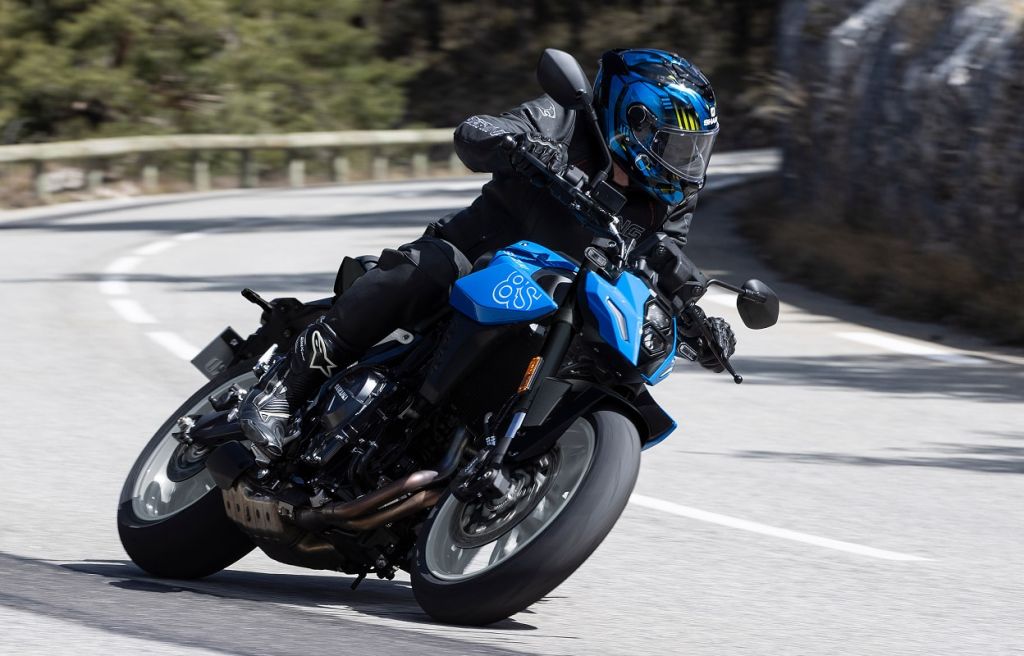 Blaues Suzuki-Naked-Bike mit Fahrer in Motorradkleidung nimmt eine Kurve auf einer Bergstraße.