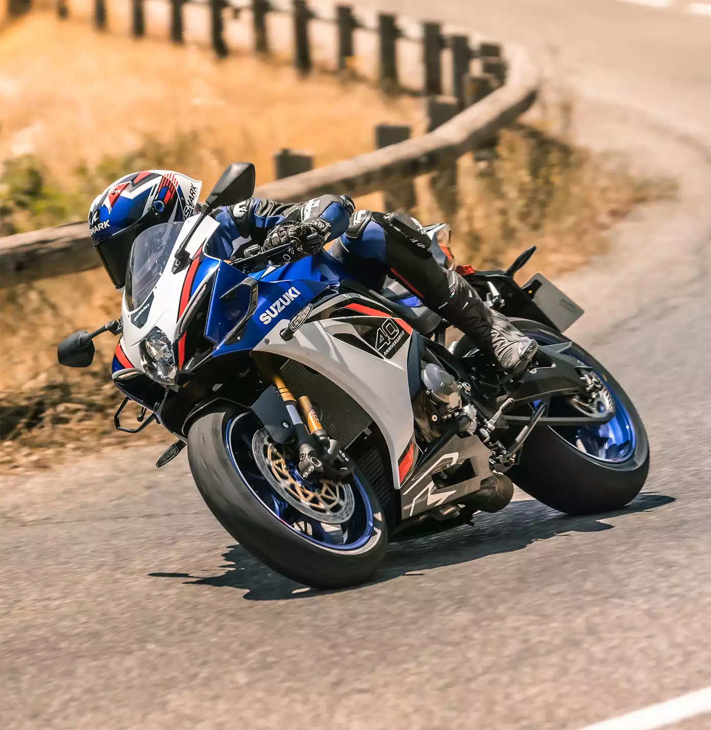 Suzuki GSX-R1000R in Weiß-Blau-Rot in sportlicher Schräglage auf einer Landstraße.