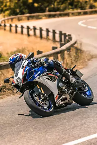 Suzuki GSX-R1000R in weiß-blau-rot, sportliche Schräglage in einer Kurve auf der Landstraße