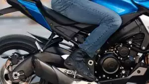 Person auf Suzuki-Motorrad in blauer Jeans und schwarzen Schuhen