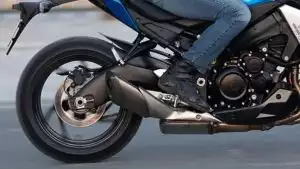Motorradfahrer auf Suzuki-Motorrad in Bewegung, Fokus auf Hinterrad und Auspuff.