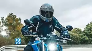 Fahrer auf einer blauen Suzuki GSX-S950 auf kurviger Landstraße.