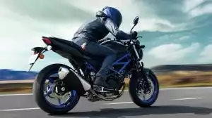 Motorradfahrer auf Suzuki-Motorrad bei hoher Geschwindigkeit auf offener Straße.