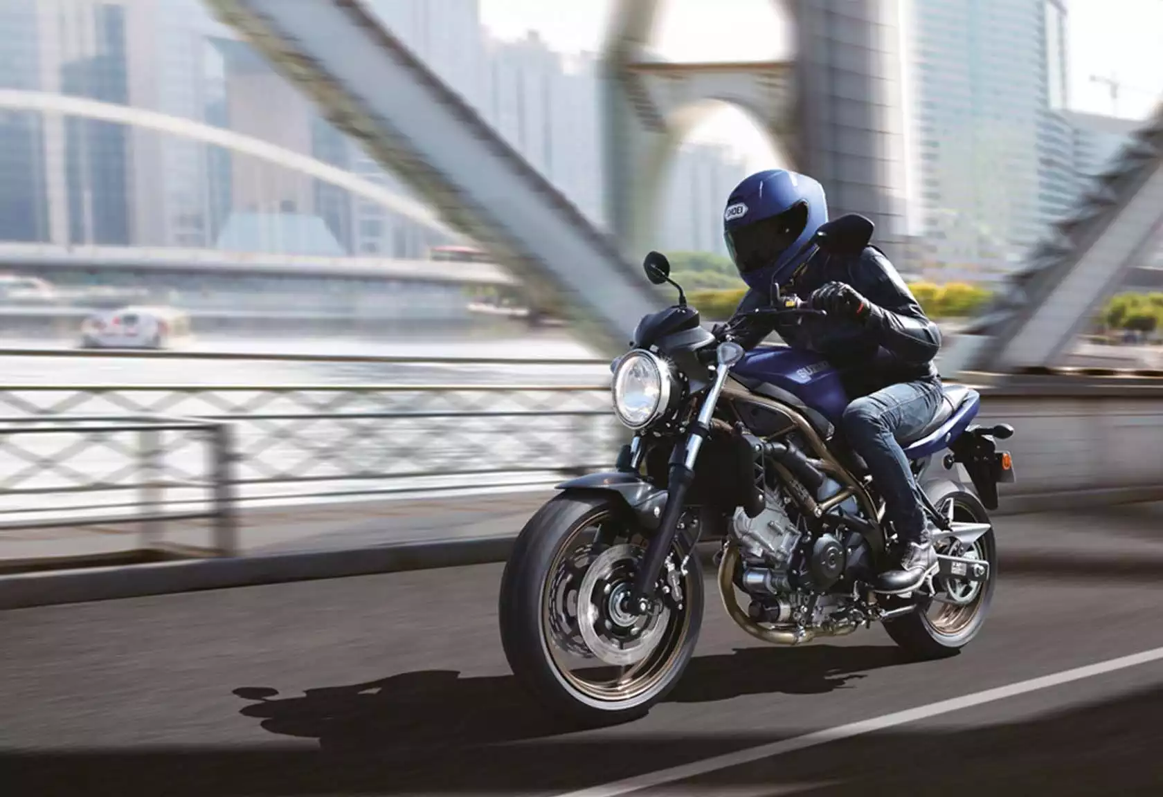 Fahrer auf Suzuki SV650 Motorrad auf einer Brücke in urbaner Umgebung.