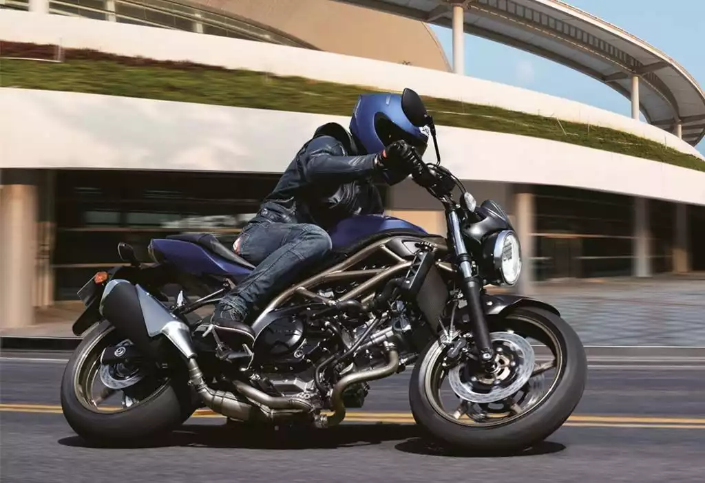 Fahrer auf Suzuki SV650 Motorrad vor moderner Architektur